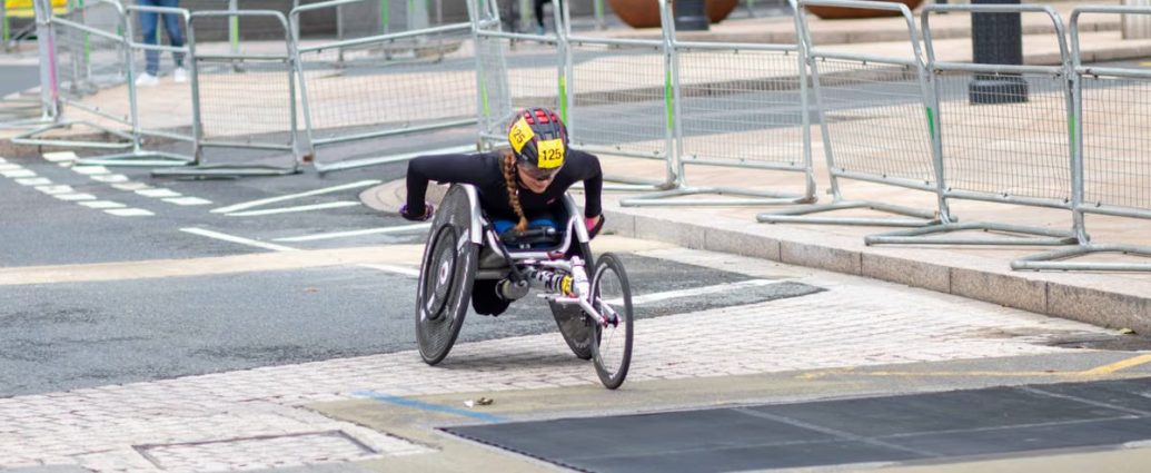 A dedicated athlete competes in a marathon using a racing wheelchair on city streets.